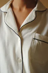 Conjunto de pijama de algodón gris con estampado geométrico blanco, compuesto por una camisa de manga larga con botones y un pantalón largo con elástico en la cintura.