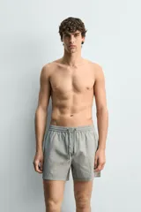 Short de baño confeccionado en tejido técnico con patrón de rayas verticales en tonos azul marino y blanco, con cintura elástica ajustable mediante cordón y bolsillos laterales.