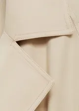 Abrigo largo tipo trench de diseño recto y fluido, con cuello de solapas con muesca, cierre delantero, cinturón tipo batín y mangas largas con trabillas.