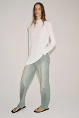 Jeans de tiro bajo y corte recto, confeccionados en denim con estampado de rayas verticales y efecto lavado. Presenta cinco bolsillos, trabillas en la cintura, cierre frontal con cremallera y botón, y un detalle de rotura en la parte delantera.