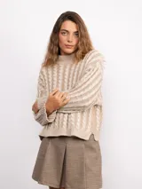 Sweater de punto con diseño de trenzas verticales, cuello alto y corte holgado. Presenta mangas largas con puños acanalados y un largo a la cadera.