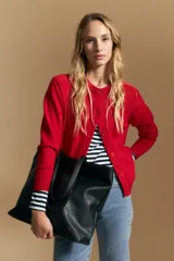 Cardigan de tejido de punto color rojo, con cuello redondo, cierre frontal de botones al tono y puños acanalados.
