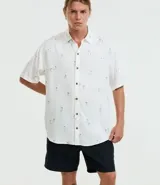 Camisa de viscosa con estampado de palmeras, corte relaxed, cuello inglés, manga corta y botones contrastantes.