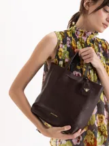 Cartera tipo tote bag pequeña de cuero vacuno negro con diseño de abejas grabadas en bajo relieve. Cuenta con doble asa de mano, correa ajustable y un tag colgante con dije metálico en forma de abeja.