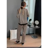 Conjunto de pijama de dos piezas compuesto por una camisa de manga larga con cuello mao y cierre frontal de botones, y un pantalón largo. Presenta un diseño estampado de corazones sobre fondo negro con detalles en color blanco.