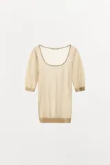 Top de punto fino semitransparente, color beige, con escote redondo y mangas cortas con puños ajustados.