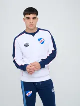 Buzo deportivo azul marino con detalles en rojo y blanco en cuello, hombros y mangas, de cuello redondo y manga larga, con el logo de Umbro y el escudo del Club Nacional de Football bordados en el pecho.