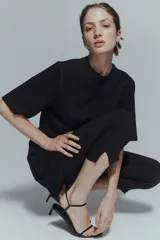 Vestido corto de algodón en punto suave, color negro, con cuello redondo acanalado, mangas al codo y costura visible central en el delantero y la espalda.