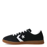 Championes Converse All Star de corte bajo, confeccionados en gamuza negra con el icónico logo de estrella y chevrón en blanco en el lateral. Presentan cordones blancos, interior acolchado y suela de goma color caramelo.