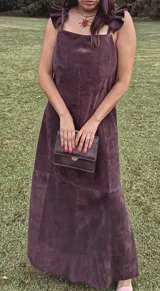 Vestido largo de gamuza color bordó, con escote cuadrado y breteles anchos con volados. Presenta un diseño de corte recto y tajo trasero para mayor movilidad.