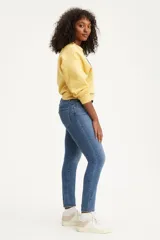 Jean de corte skinny y tiro alto, confeccionado en denim azul con lavado medio. Presenta diseño clásico de cinco bolsillos y cierre frontal con botón y cremallera.