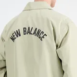 Campera color verde claro con cierre de botones a presión, cuello camisero y logo de New Balance bordado en el pecho. Corte recto y mangas largas.