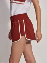 Short deportivo color ladrillo con ribete blanco, de corte clásico inspirado en la ropa deportiva.