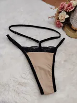 Tanga de diseño moderno en color beige con detalles en encaje negro y tiras elásticas regulables.