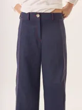 Pantalon de pierna ancha color azul marino, con costuras decorativas en contraste de color rojo y franjas laterales a tono. Cuenta con cintura alta, cierre frontal y bolsillos laterales.