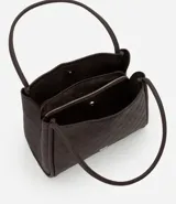 Cartera modelo hobo de gran tamaño, confeccionada en poliuretano con textura geométrica triangular. Presenta asas tubulares largas para llevar al hombro, cierre superior con cremallera y un pequeño aplique metálico dorado en la parte frontal.