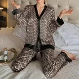 Conjunto de pijama de dos piezas compuesto por una camisa de manga larga con cuello mao y cierre frontal de botones, y un pantalón largo. Presenta un diseño estampado de corazones sobre fondo negro con detalles en color blanco.