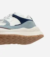 Championes estilo jogging con diseño de recortes contrastantes en tonos blanco, azul y gris. Presenta una parte superior de mesh respirable con sobreposiciones de poliuretano, forro suave y suela robusta de color crema con base marrón.