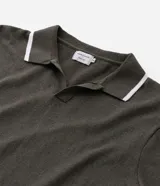 Camisa polo de manga corta color verde oliva, confeccionada en tejido de punto, con cuello y puños con ribetes contrastantes en blanco y rojo.