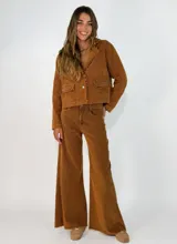 Chaqueta de pana color marrón, con solapas desflecadas, cierre frontal con botones y bolsillos delanteros con solapa desflecada.