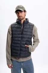 Chaleco capitoneado negro con cierre frontal, cuello alto y bolsillos laterales.