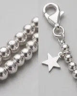 Pulsera de plata elaborada con cuentas esféricas texturizadas y dos dijes colgantes en forma de estrella.