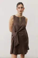 Vestido corto blanco sin mangas, con cuello redondo y detalle de nudo drapeado en el lateral.