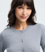 Cardigan de punto color gris, con cuello redondo, manga larga y cierre frontal con botones. Presenta puños y bajo acanalados, con un diseño clásico y versátil.