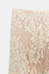 Pantalón bombacho de tiro alto con cintura elástica y puños ajustados, confeccionado en encaje color crudo con forro interior corto a tono.