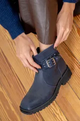Bota corta de cuero azul con suela track negra, detalle de tira con hebilla metálica y tachas decorativas en el tobillo.