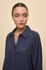 Camisa negra de calce relajado, con mangas 3/4, cuello clásico y cierre frontal con botones. Presenta detalles calados en la parte superior.