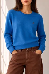 Sweater de punto color beige, de cuello redondo y manga larga, con detalle de pequeño bordado en el pecho.