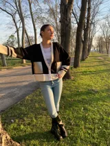 Cárdigan de tejido fino con diseño tricolor en negro, blanco y beige. Presenta escote en V con cierre frontal de botones, mangas largas con puños acanalados y bolsillos frontales con detalle en cuero.