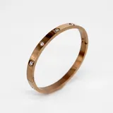 Pulsera rígida color oro rosa con cristales incrustados de circonia cúbica.