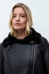 Chaqueta biker de cuero sintético negro con interior y solapas de piel sintética al tono. Presenta cierre frontal cruzado, mangas largas y textura granulada.