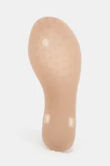 Sandalia plana tipo ojota con suela baja de color nude y tira delantera transparente de vinilo con división para el dedo.
