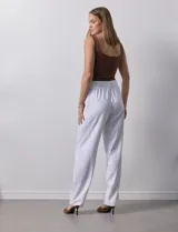 Pantalón blanco de lino con lazo en la cintura, corte recto y bolsillos laterales.