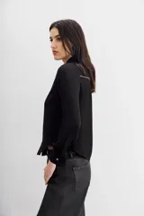 Camisa de estilo texano en color negro, con mangas largas, cuello camisero y cierre frontal con botones metálicos. Presenta un diseño con tachas termo fijadas en la zona del canesú delantero.