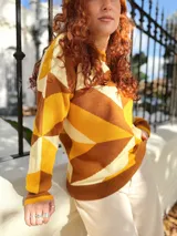 Sweater de punto con diseño geométrico en tonos mostaza, marrón y beige.