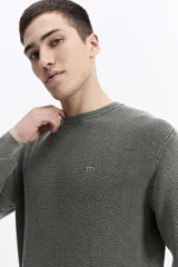 Sweater de hombre con textura waffle, color verde oliva desgastado (acid wash), cuello redondo y puños y ruedo acanalados. Presenta un pequeño logo bordado en el pecho.