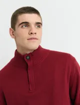 Sweater de punto color tostado, con cuello alto y cierre frontal parcial con botones. Diseño de manga larga con puños y ruedo acanalados.