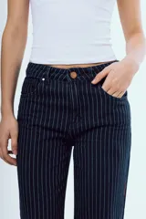 Pantalón de jean azul oscuro de corte recto y tiro medio, con diseño de rayas diplomáticas blancas. Presenta bolsillos delanteros y traseros, y cierre frontal con botón y cremallera.