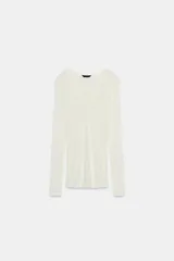 Camiseta blanca de manga larga, corte slim fit y escote pico pronunciado. Tejido ligero y ligeramente transparente con textura acanalada.