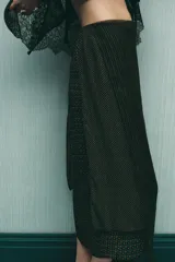 Falda tipo pareo de tiro bajo con estampado geométrico en tonos verdes y naranjas. Confeccionada en viscosa 100%, tiene un bajo asimétrico y cierre lateral con cremallera oculta.