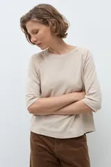 Remera de manga tres cuartos con diseño raglán y detalle de costura decorativa en los hombros. Presenta cuello redondo y un corte clásico.