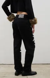 Pantalón de denim negro de corte recto con estampado floral blanco en ambas piernas. Cuenta con cierre frontal y bolsillos laterales.