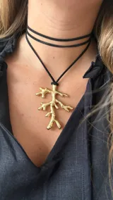 Collar con cordón marrón y dije dorado en forma de rama.