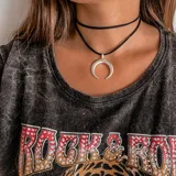 Gargantilla de cuero negro con dije de medialuna plateada.