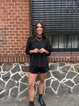 Camisa blanca de manga larga con detalles de encaje o bordado en el canesú y el frente. Presenta un corte holgado y mangas con puños elásticos o fruncidos.