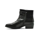 Bota corta de cuero negro con taco bajo cuadrado y punta redondeada. Presenta tres correas horizontales con hebillas metálicas plateadas y detalle de tachas metálicas en la puntera.